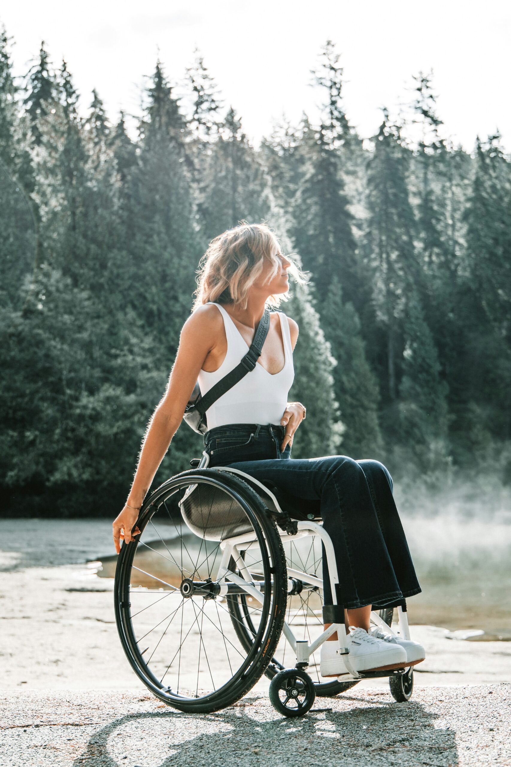 A person using a wheelchair outdoors on a quiet forest path